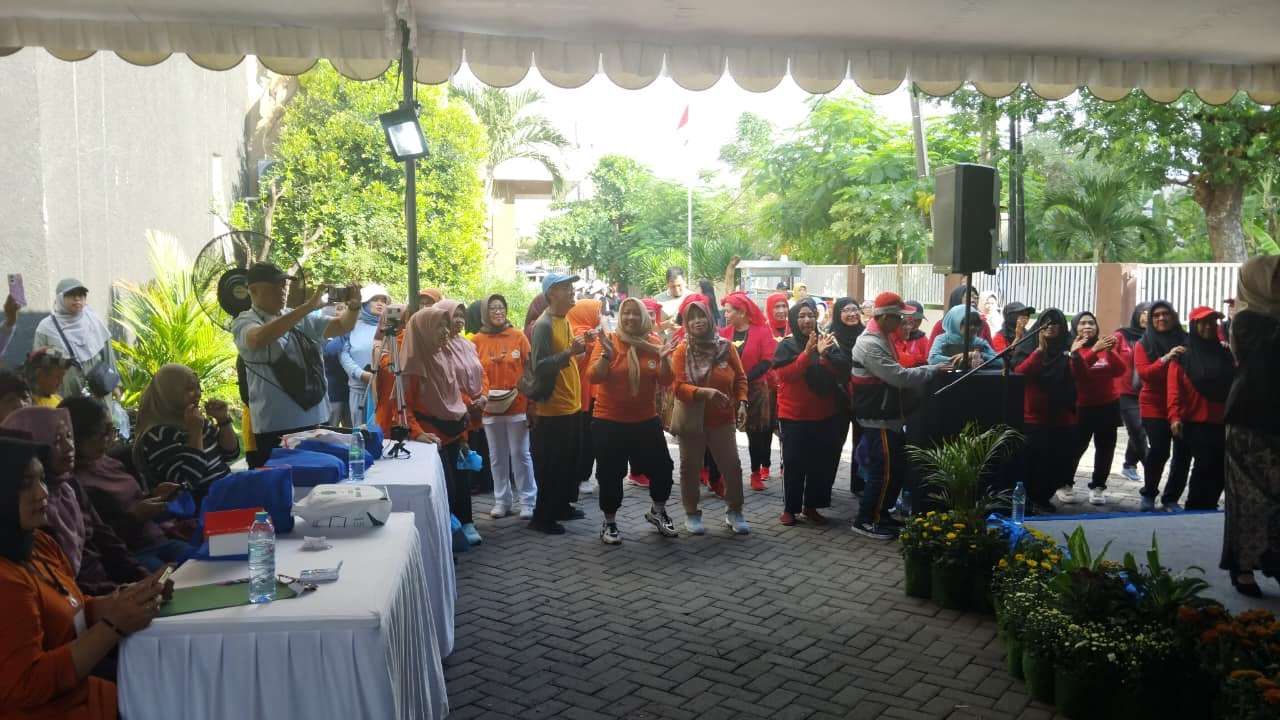 Situasi di samping panggung utama perayaan Hari Lanjut Usia Nasional (HLUN) di halaman Kantor Kecamatan Gunung Anyar yang dipadati penonton. Beberapa warga tampak mengabadikan momen menggunakan ponsel, sementara yang lain bertepuk tangan memberikan dukungan bagi peserta yang tampil. (jatimsport.com/Keyzei Zahir)